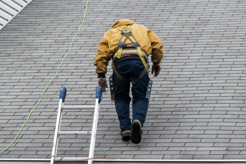 roof tech walking up a sloped roof near a ladder