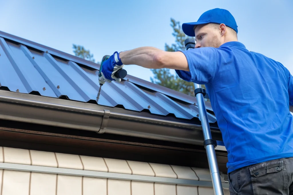 roof tech installing metal roofing on a home while standing on a ladder