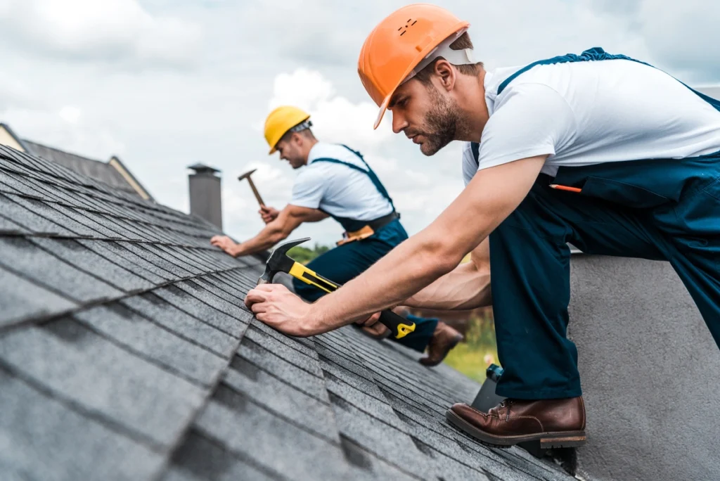 2 roof technicians installing shingles on a sloped roof