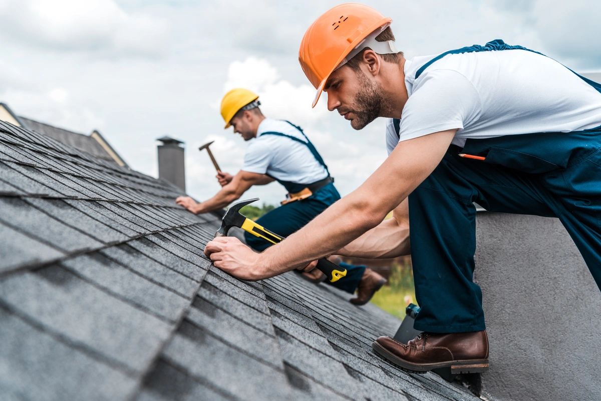 2 roof technicians installing shingles on a sloped roof