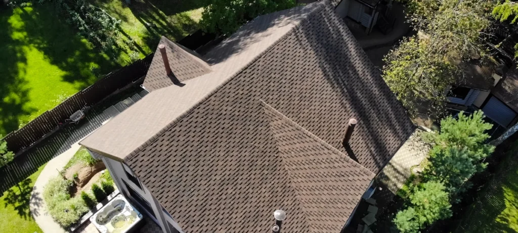 arial view of a brown roof on a home surrounded by trees