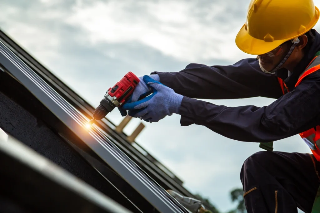 roof technician in a hard hat using power tools to install roofing on a home
