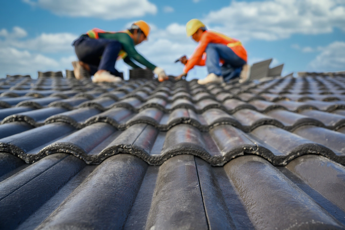2 roof technicians installing shingles on a sloped home roof